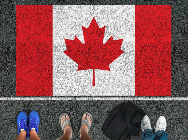 A set of four feet standing in front of a red and white Canadian flag painted on black pavement.