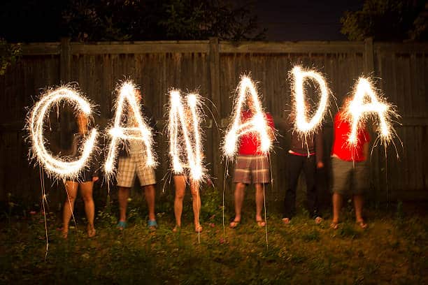 Persons standing with sparklers, spelling out the word "Canada".